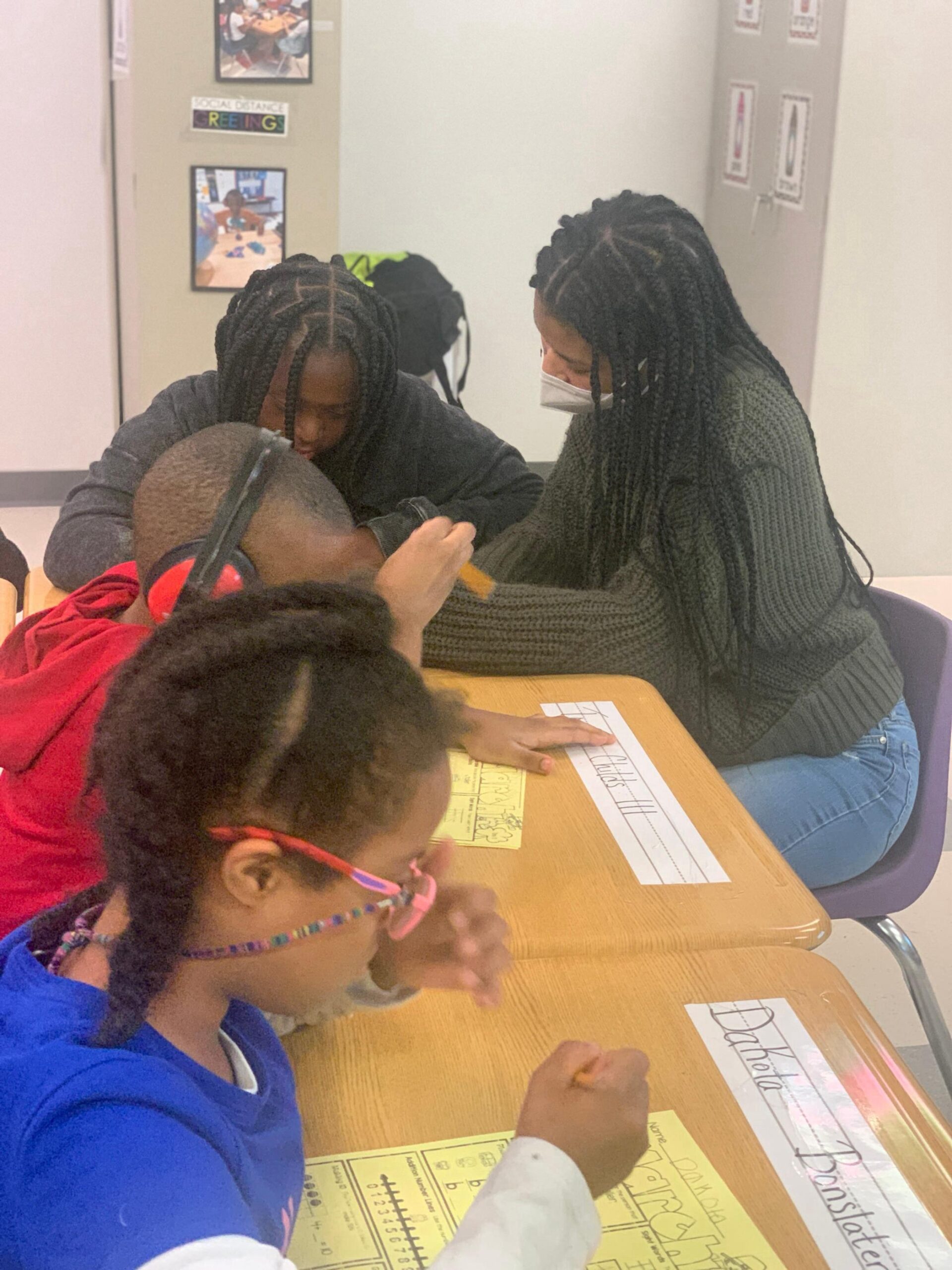 Founder Eden Wilson in a classroom sitting at a desk helping a student with handwriting